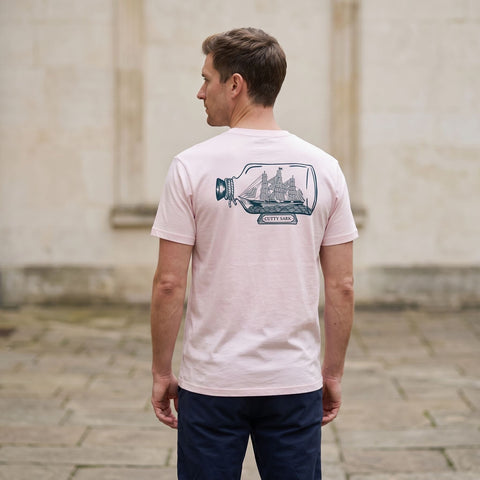 Man wearing a pink t-shirt with Cutty Sark ship in bottle print on the back
