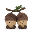 Two cute acorn plush toys sitting side by side on a white background. Each acorn has a brown fuzzy cap, a beige textured body, embroidered black eyes and smile, and dark brown feet.