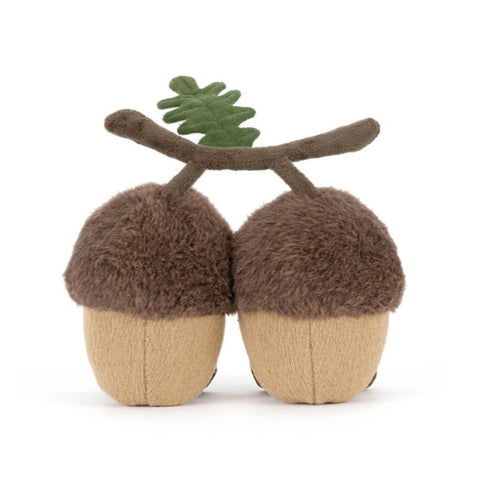 A pair of plush acorn-shaped toys with fuzzy brown caps, tan soles, and a small green leaf on a brown branch