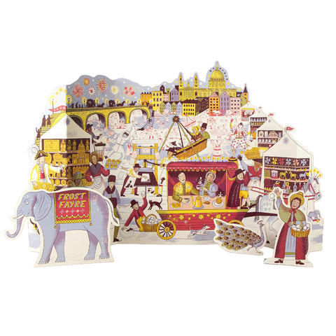 A colorful 3D pop-up cardboar Advent Calendar depicting a winter fair scene with a snowman, an elephant carrying a sign that reads 'FROST RAYE', a carousel, market stalls, and whimsical characters