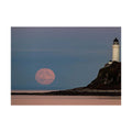 Moon rise up over the distant skyline and a lighthouse on a cliff