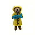 Bear in a yellow raincoat holding a blue fish 