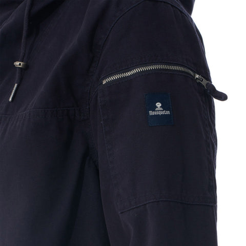 Close-up of a dark navy hooded jacket sleeve showing a zippered pocket with a blue brand patch on the upper arm.