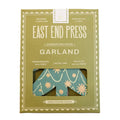 East End Press Concertina Paper Garland packaging in olive green, featuring a clear window that reveals a teal and beige patterned paper garland inside.