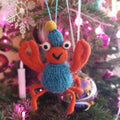 Knitted crab ornament hanging on a Christmas tree with colorful lights.