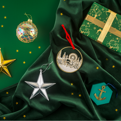Gold star, silver star, gold bauble, London skyline hanging decoration and Cutty Sark anchor decorations against a green background