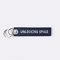Keychain with 'Unlocking Space' text on a white background