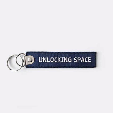 Keychain with 'Unlocking Space' text on a white background