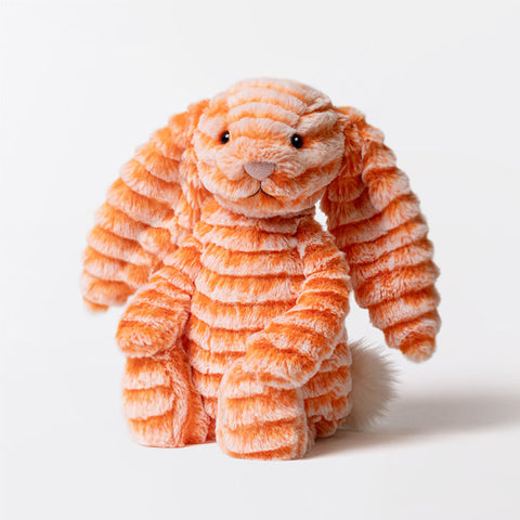 Orange plush soft toy bunny with long ears and a fluffy tail