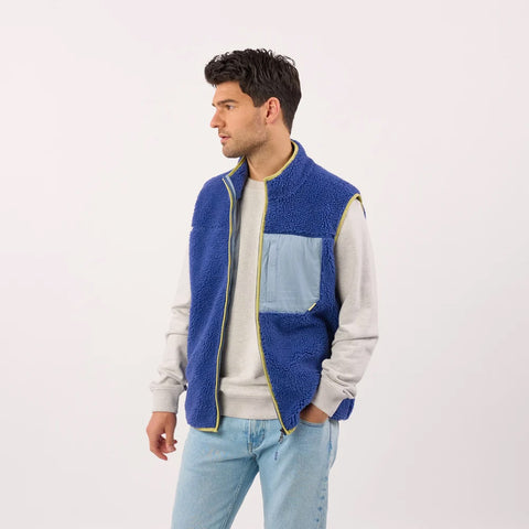 Man wearing a blue fleece vest over a light gray sweater 