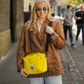 Woman holding a yellow bag on a city street
