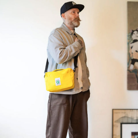 Man wearing a yellow bag over his shoulder in an indoor setting