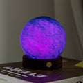 Purple glowing sphere on a wooden base with a blurred background