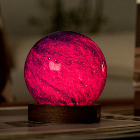 Pink glowing sphere on a wooden base with a blurred background