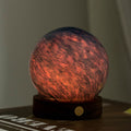 Decorative sphere with a red and blue pattern on a wooden base against a neutral background