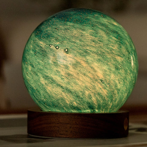 Spherical lamp with green and yellow marbled pattern on a wooden base
