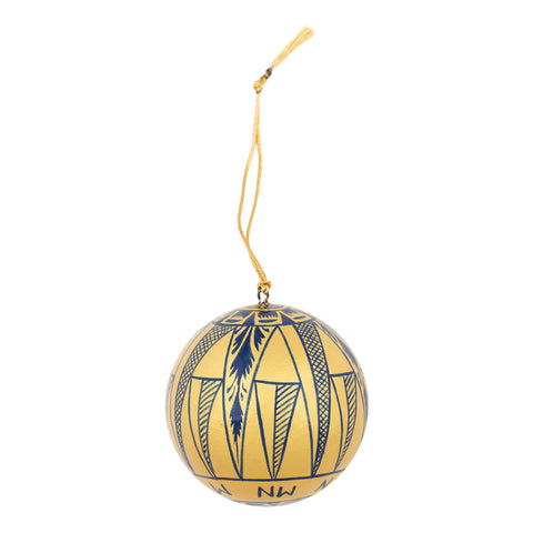 A spherical gold ornament decorated with blue geometric patterns and compass directions, hanging from a gold cord with a tassel