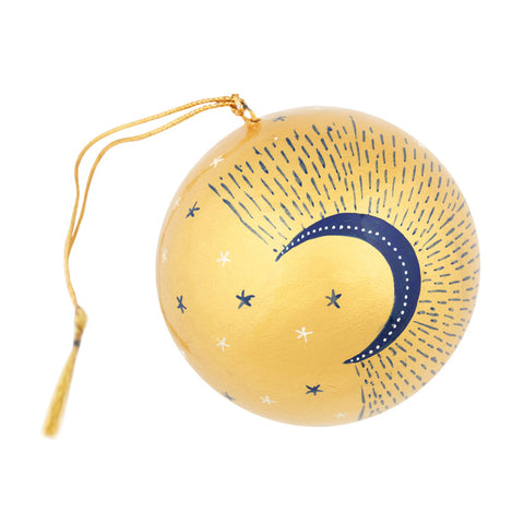 A round gold-colored hanging ornament decorated with a navy blue crescent moon, white stars, and radiating dotted lines