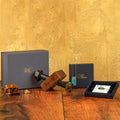 Decorative items including a wooden dumbbell, metal bolts, and a black box on a wooden surface with a gold textured background.