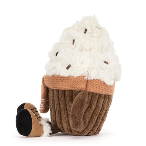 A plush toy with fluffy white frosting, a brown ribbed wrapper, and a small dangling boot on the side