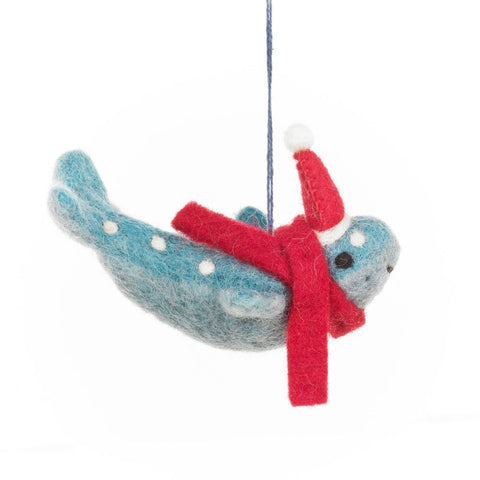 Felted wool ornament of a blue whale with a red scarf and white polka dots on a white background