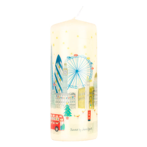 A cream-colored cylindrical pillar candle featuring a hand-painted illustration of London landmarks, including the Guggenheim, Big Ben, the London Eye, a red double-decker bus, and a Christmas tree