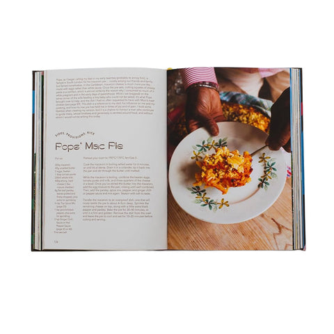 Open book showing a recipe for 'Popo's Mac Fie' with a plate of food on a wooden table.