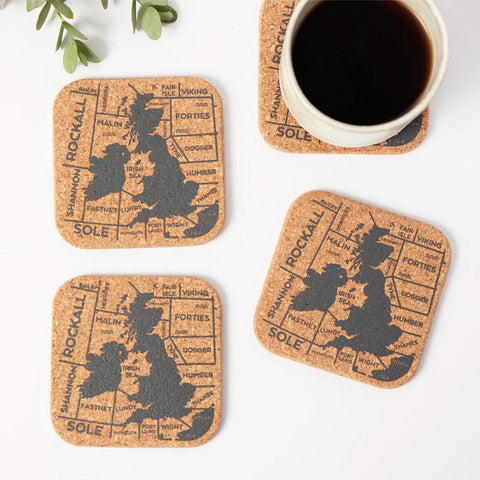 Set of four cork coasters with map design on a white surface with a cup of coffee.