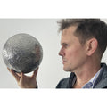 Luke Jerram holding a mini Mirror Moon sculpture