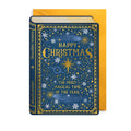 A Christmas card designed as a hardcover book titled 'Magical Christmas' with a navy blue cover decorated with gold and white festive illustrations, shown in front of a yellow envelope on a white background.