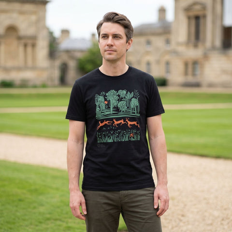 Man wearing a black t-shirt with a graphic design standing in front of a historic building.