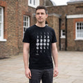 Man wearing a black t-shirt with white moon phase print and 'Royal Museums Greenwich' logo.