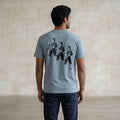 Man wearing a light blue t-shirt with a graphic design of three astronauts on the back, standing against a plain wall.