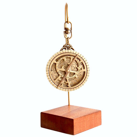 Gold astrolabe on a wooden stand showing detailed dials, numbers and star-sign symbols