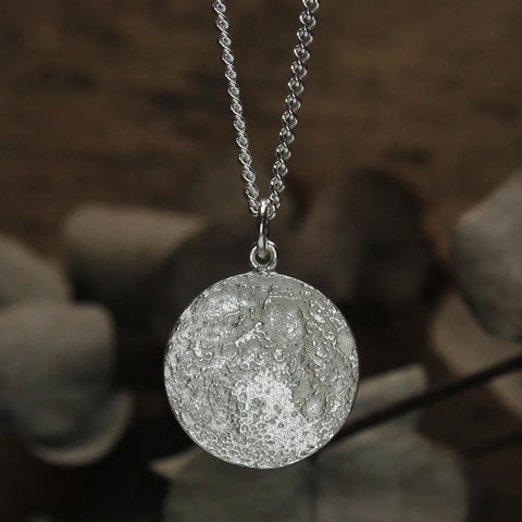 Silver necklace with textured pendant resembling the Moon.