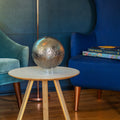 Decorative moon sphere on a table with blue and green chairs in the background
