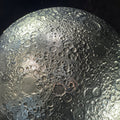 Close-up of the textured surface of a steel sculpture of the Moon