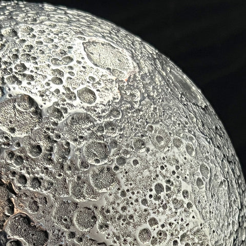 Close-up of a textured surface of a Moon sculpture showing craters on the Lunar surface