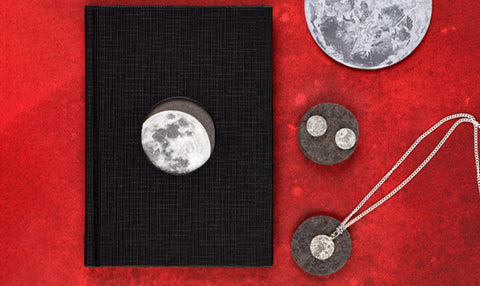 Moon-themed jewelry and book on a red background