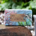 Bar of soap with ocean-themed packaging featuring a turtle and seaweed, labeled 'Ocean Seaweed' on a natural stone surface.