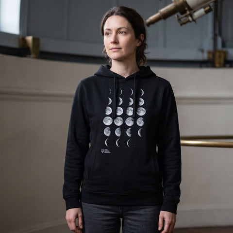 Woman wearing a black hoodie with moon phase design in an observatory setting