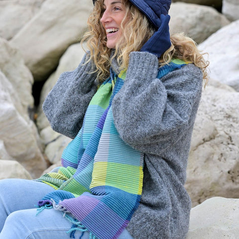 Woman sitting on rocks wearing a colorful scarf and gray sweater