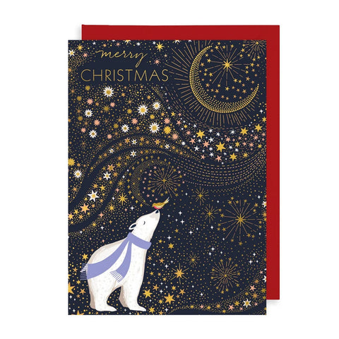 A Christmas greeting card featuring a white polar bear wearing a lavender scarf under a gold crescent moon and starry night sky, with the words 'merry CHRISTMAS' at the top. A red envelope is partially visible behind the card