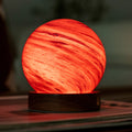 Spherical lamp with red and orange swirl pattern on a dark background