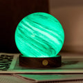 Marble-patterned lamp emitting a green glow on a surface with a blurred background
