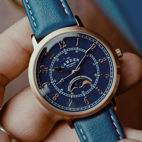 Close-up of rose-gold watch with blue face and blue leather strap.