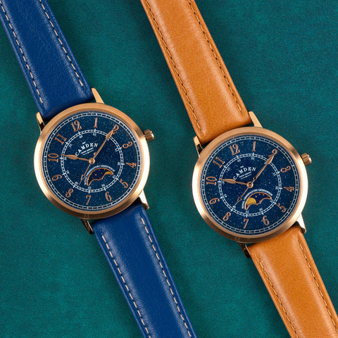 Two rose-gold watches with blue faces and leather straps, one blue, one tan.