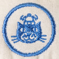 Embroidered design of a cat with a blue border on beige fabric