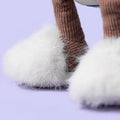 Close-up of a plush toy with white fur and brown legs on a light purple background