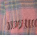 A close-up of a soft plaid scarf in dusty pink with blue and yellow stripes, finished with fringed edges.